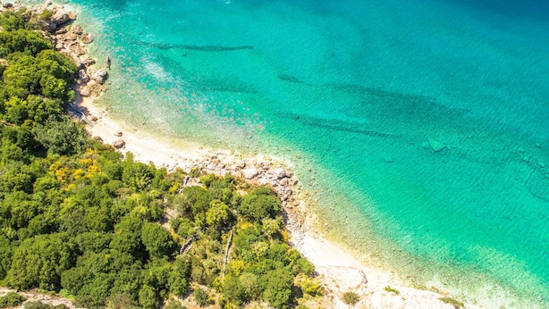 An aerial view of a coastal area with clear turquoise waters, rocky shoreline, and dense green vegetation. - Nice Home in Stara Baska 1 With Wifi and 0 Bedrooms (Punat)