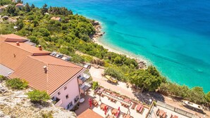 A coastal property with a patio area, a view of the sea, and a building with a red-tiled roof. - Nice Home in Stara Baska 1 With Wifi and 0 Bedrooms (Punat)