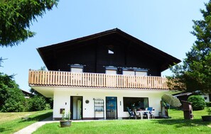 Chalet-style building with a balcony and a small entrance, set amidst a serene natural setting.