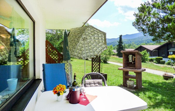 Enjoy a serene view of the surrounding countryside from this room's large window, featuring a bird's eye view of a mountain range and a nearby cabin.