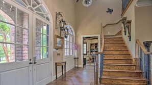 A spacious foyer with a wooden staircase, a large arched window, and a door leading to another room. - Families Welcome! Lavish Celina Home w/ Game Room (Celina)
