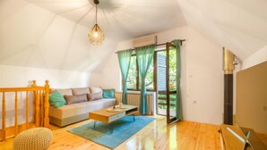 Ein gemütliches Wohnzimmer mit Holzboden, einer Couch, einem Couchtisch und einer Pendelleuchte.