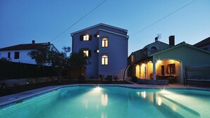 A swimming pool with a view of a two-story building with multiple windows and a patio area with outdoor seating. - Stunning Apartment in Zadar With 2 Bedrooms, Wifi and Outdoor Swimming Pool (Zadar)