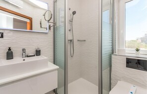 A modern bathroom with a glass-enclosed shower, a white sink with a mirror, and a window with a view of the city. - 2 bedroom cozy home in Sukosan (Sukosan)