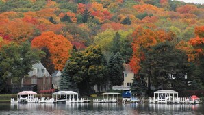 A lakeside view with docked boats, a gazebo, and a hill with autumn foliage. -  Beautiful Abbey Springs Gated Golf Cart Community with Beach, Pools, & Golf (Fontana-on-Geneva Lake)