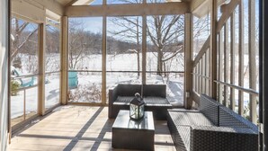 A covered porch with wicker furniture and a glass coffee table. -  Beautiful Abbey Springs Gated Golf Cart Community with Beach, Pools, & Golf (Fontana-on-Geneva Lake)