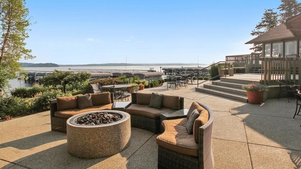 An outdoor patio with seating, a fire pit, and a view of the water. -  Beautiful Abbey Springs Gated Golf Cart Community with Beach, Pools, & Golf (Fontana-on-Geneva Lake)