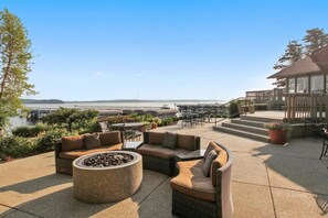 Un patio al aire libre con asientos, una chimenea y vista al agua.