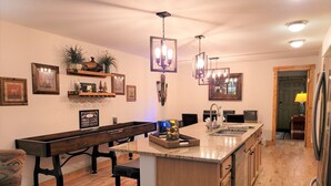 A kitchen with a central island, wooden cabinets, a built-in bench, pendant lighting, and wall-mounted shelves with decorative items. - Downtown Fun! A/C shufflebrd Pacman, Steps Fm SkiBus, DogOK, walk to Yampa River (Steamboat Springs)