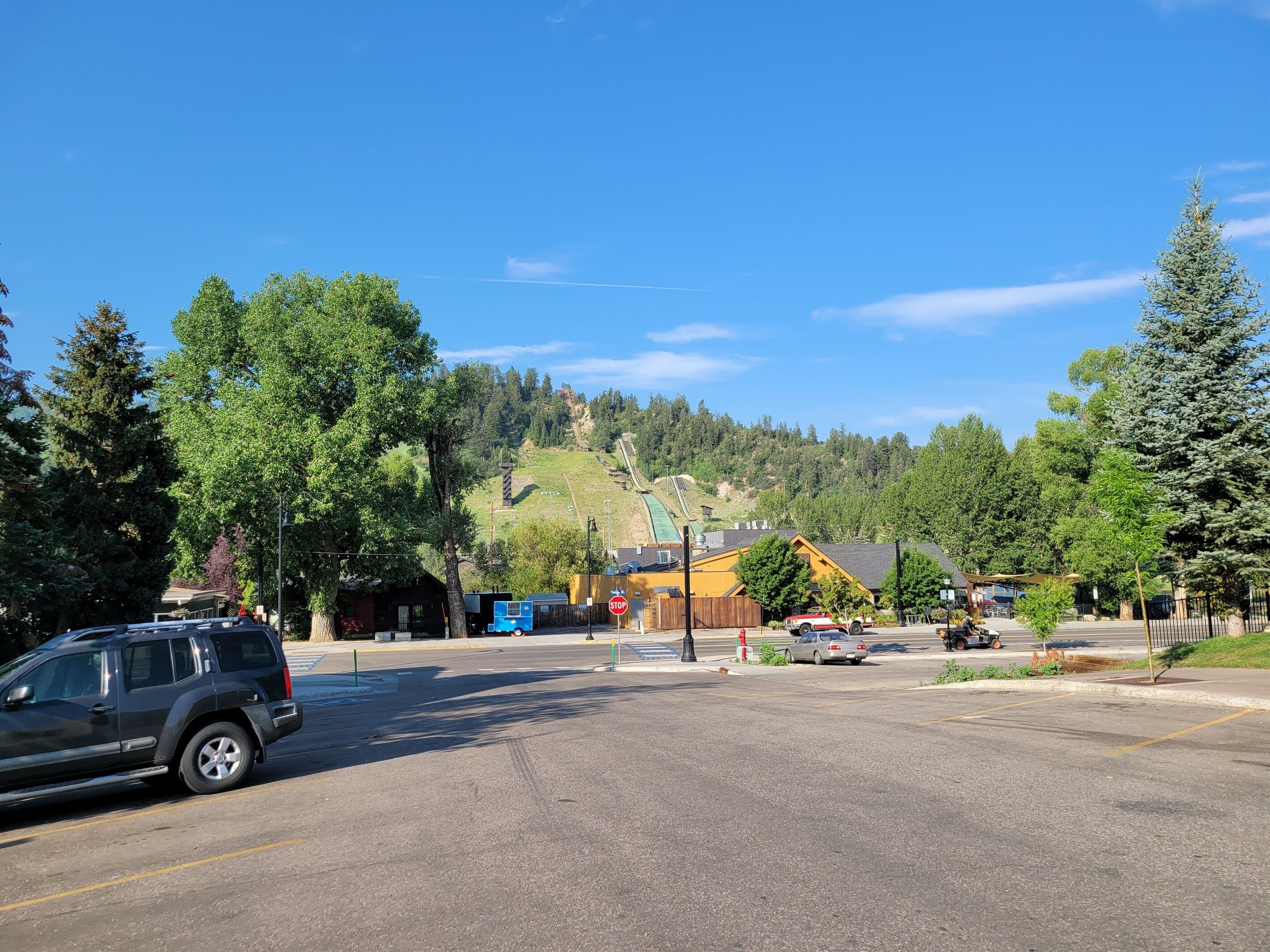 A parking lot with a stop sign, a blue food truck, and a yellow building in the background.