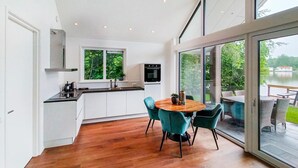 A modern kitchen with white cabinets, a black oven, and a window overlooking greenery.