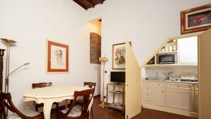 A dining area with a table and chairs, a television, and a kitchen with cabinets and a microwave. - Bardi Suite apartment near Ponte Vechhio by Mmega (Firenze)