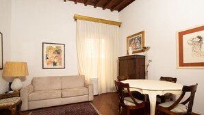 A living room with a sofa, a dining table with chairs, a patterned rug, and artwork on the walls. - Bardi Suite apartment near Ponte Vechhio by Mmega (Firenze)