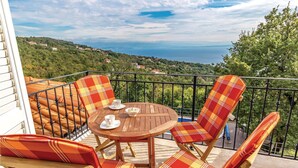A balcony with a round wooden table, two chairs with plaid cushions, and a view of a coastal landscape. - Stunning Home in Icici With Wifi and 2 Bedrooms (Opatija)