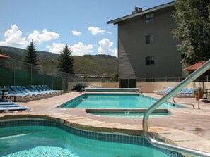 Una piscina con sillas de descanso y un edificio al fondo.