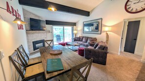 A cozy living room with a fireplace, a dining table, and a comfortable seating area. - Luxury Condo w/ FREE WiFi, Parking, Heated Pool, Hot Tubs, Skier Shuttles (Avon)