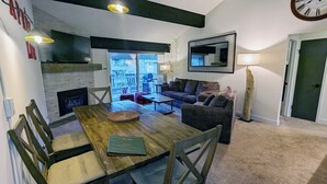 A cozy living room with a fireplace, a dining table, and a sofa. - Luxury Condo w/ FREE WiFi, Parking, Heated Pool, Hot Tubs, Skier Shuttles (Avon)