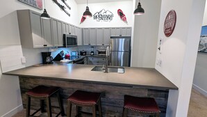 A modern kitchen with grey cabinets, stainless steel appliances, and a central island with stools. - Luxury Condo w/ FREE WiFi, Parking, Heated Pool, Hot Tubs, Skier Shuttles (Avon)