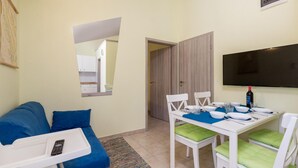 A compact living space with a kitchenette, a dining area with a TV, and a blue sofa. - Nice Apartment in Kosljun With Wifi and 1 Bedrooms (Pag)