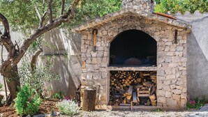Un four extérieur en pierre, avec un espace de stockage pour le bois de chauffage situé en dessous.