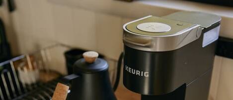 Una cafetera Keurig sobre una mesa de madera con un cajón que contiene cápsulas de café.