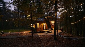 Eine kleine Holzhütte mit geneigtem Dach, einer Veranda und einer Lichterkette.