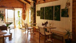 Ein gemütliches Holzinterieur mit Essbereich, Holzbalkendecke und Topfpflanzen.