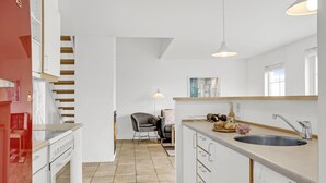 A modern kitchen with white cabinetry, a stainless steel sink, and a dining area with a chair and table. - Gorgeous home in Brenderup Fyn (Brenderup Fyn)