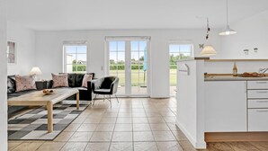 A modern living room with a sofa, a dining table, and a kitchen area with a counter and cabinets. - Gorgeous home in Brenderup Fyn (Brenderup Fyn)