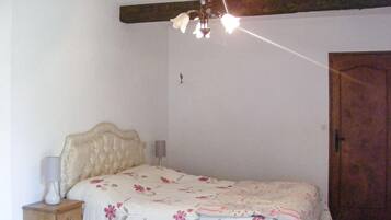 Camera da letto con un letto, un comodino, una lampada, una porta in legno e un lampadario.