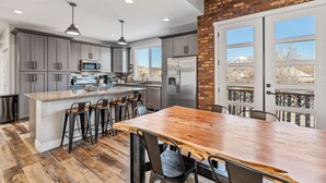 A modern kitchen with grey cabinets, stainless steel appliances, and a wooden island with bar stools.