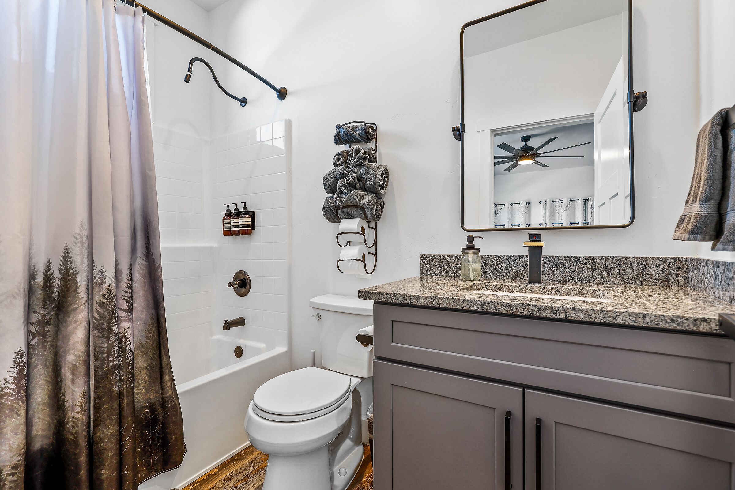 Un baño moderno con cortina de ducha, inodoro, lavabo y espejo.