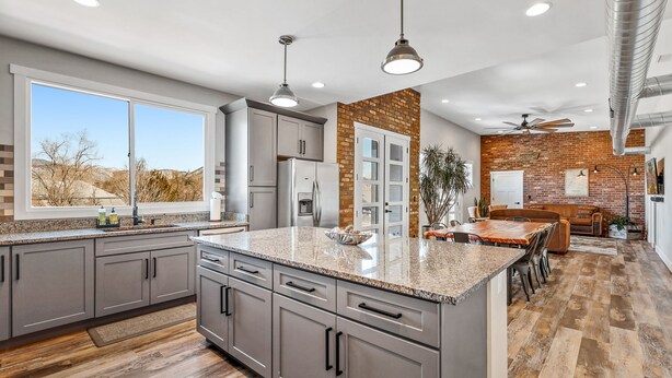 A modern kitchen with granite countertops, grey cabinets, and a large island.
