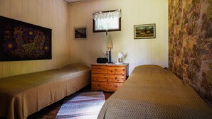 A room with two single beds, a wooden dresser, a lamp, a radio, and a painting on the wall. - 2 bedroom lovely home in Slite (Slite)