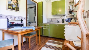 A kitchen with green cabinets, a wooden table, and a chair. There is a painting on the wall and a wooden structure on the right. - 2 bedroom lovely home in Slite (Slite)