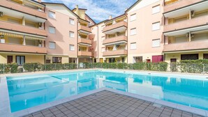 Een zwembad omringd door meerlaags appartementencomplexen met balkons.