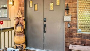 A wooden door with a bell and a welcome sign, a wooden bench, and a decorative bear statue. - Pine Mountain Cabin w/ Hot Tub, 2 Mins to Marina! (Groveland)