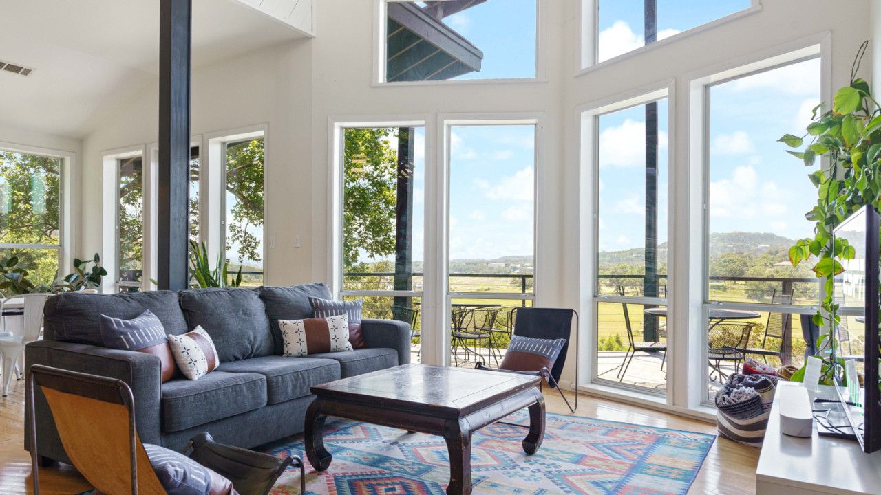 A spacious living room with a large gray sofa, a wooden coffee table, and a colorful rug.
