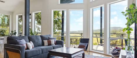 A spacious living room with a large gray sofa, a wooden coffee table, and a colorful rug.