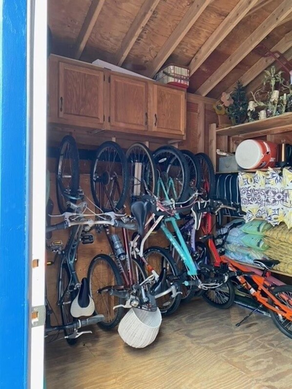 Zona de almacenamiento para bicicletas con varias bicicletas y un estante con objetos decorativos.