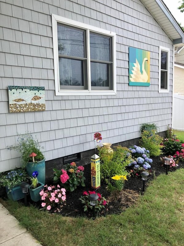 A house with a well-maintained garden, including colorful flowers and a birdhouse.