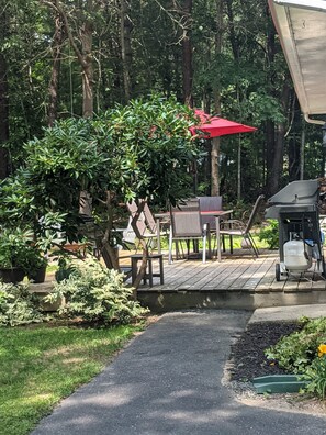 Enjoy al fresco dining on the deck surrounded by lush greenery and a grill station.