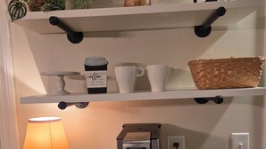 En køkkenbordplade med en kaffemaskine, en lampe og en hylde med køkkenudstyr.