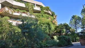 A building with multiple balconies, surrounded by dense greenery and trees. - Appartement Confortable avec Climatisation (Grospierres)
