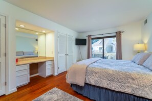 Una camera da letto con un letto, una scrivania, uno specchio, una TV e una finestra con tende.