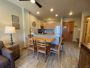 A kitchen with wooden cabinets, a stainless steel refrigerator, a dining table with four chairs, and a ceiling fan. - Dakota Lodge 8503 (Keystone)