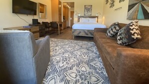 Una camera d'albergo con un letto, una scrivania, una televisione e un divano.
