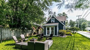 Een huis met een achtertuin, een terras, een houten hek en een kleine schuur.