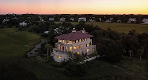 A large, multi-story house with a central courtyard, surrounded by trees and open fields.