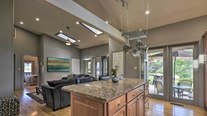 A spacious kitchen with a large island, wooden cabinets, and a view to the outdoor patio area. - Serene Mountain Retreat w/ Patio & Mtn Views! (Cortez)